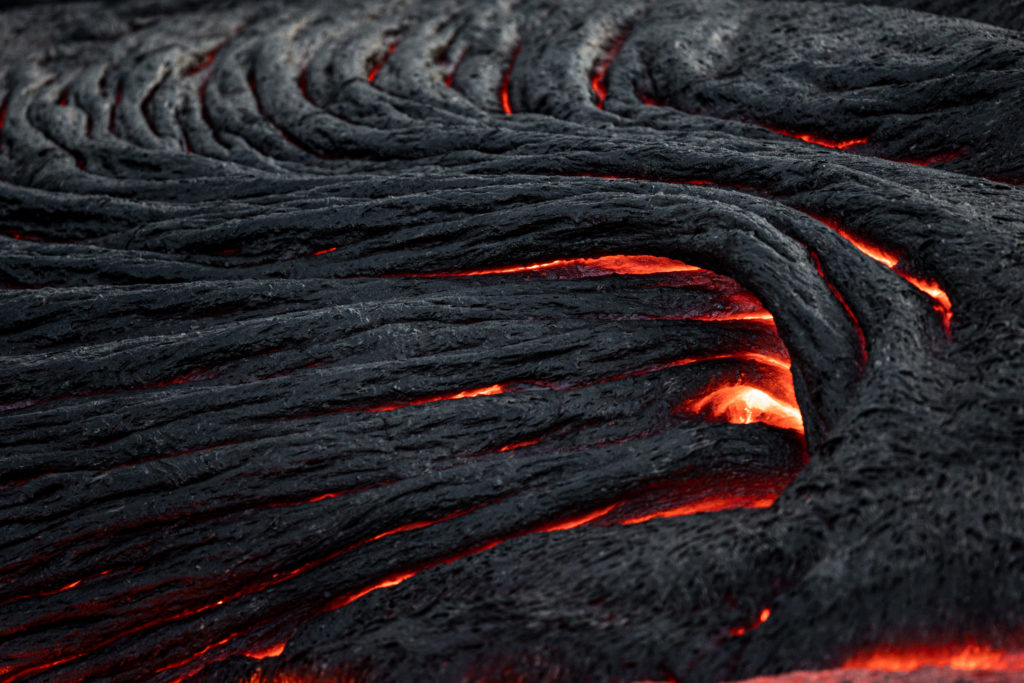 Close-up of glowing ropey pahoehoe lava cracks beneath a fresh dark crust, Geldingadalir 2021.