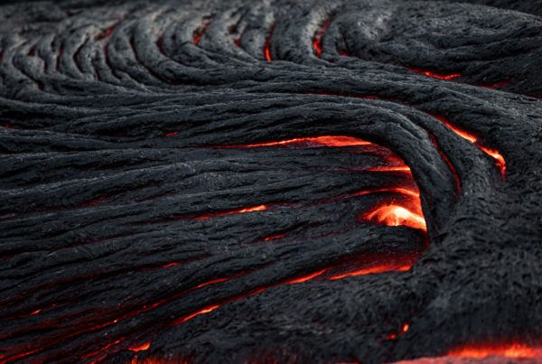 Close-up of glowing ropey pahoehoe lava cracks beneath a fresh dark crust, Geldingadalir 2021.