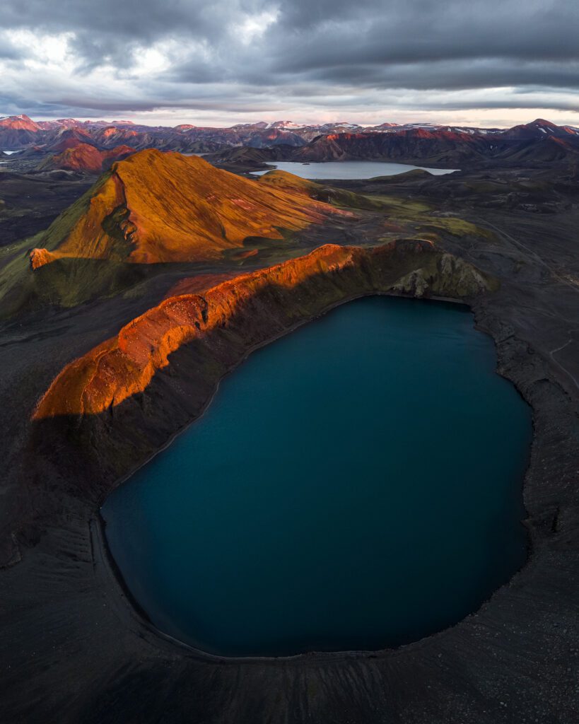 Aerial of the Bláhylur crater lake and its red volcanic rim in the Icelandic Highlands.