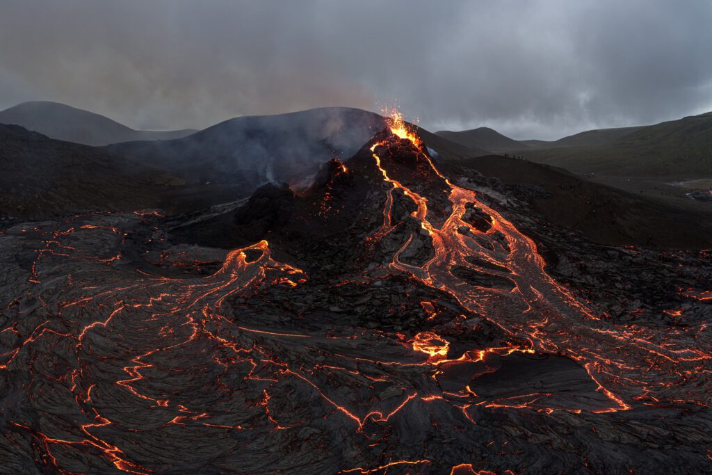 Aerial of an erupting crater with multiple lava rivers fanning across cooling fields, Fagradalsfjall.