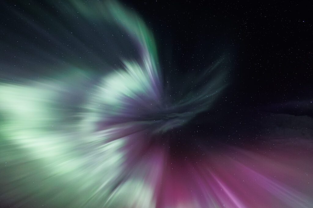Wide aurora corona looking straight up, green and magenta rays radiating across the sky.