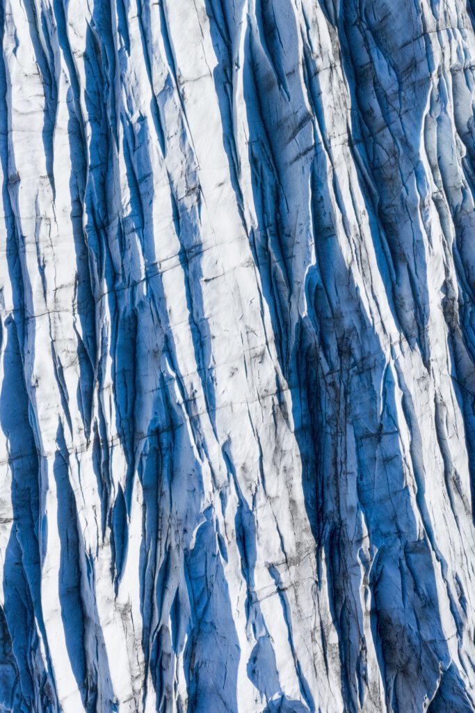 Close-up of crevassed blue Svínafellsjökull ice with dark sediment streaks running vertically.