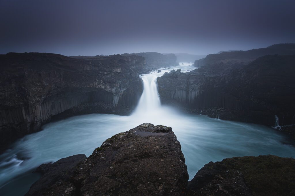 Aldeyjarfoss plunging between symmetric basalt columns into a wide turquoise plunge pool.