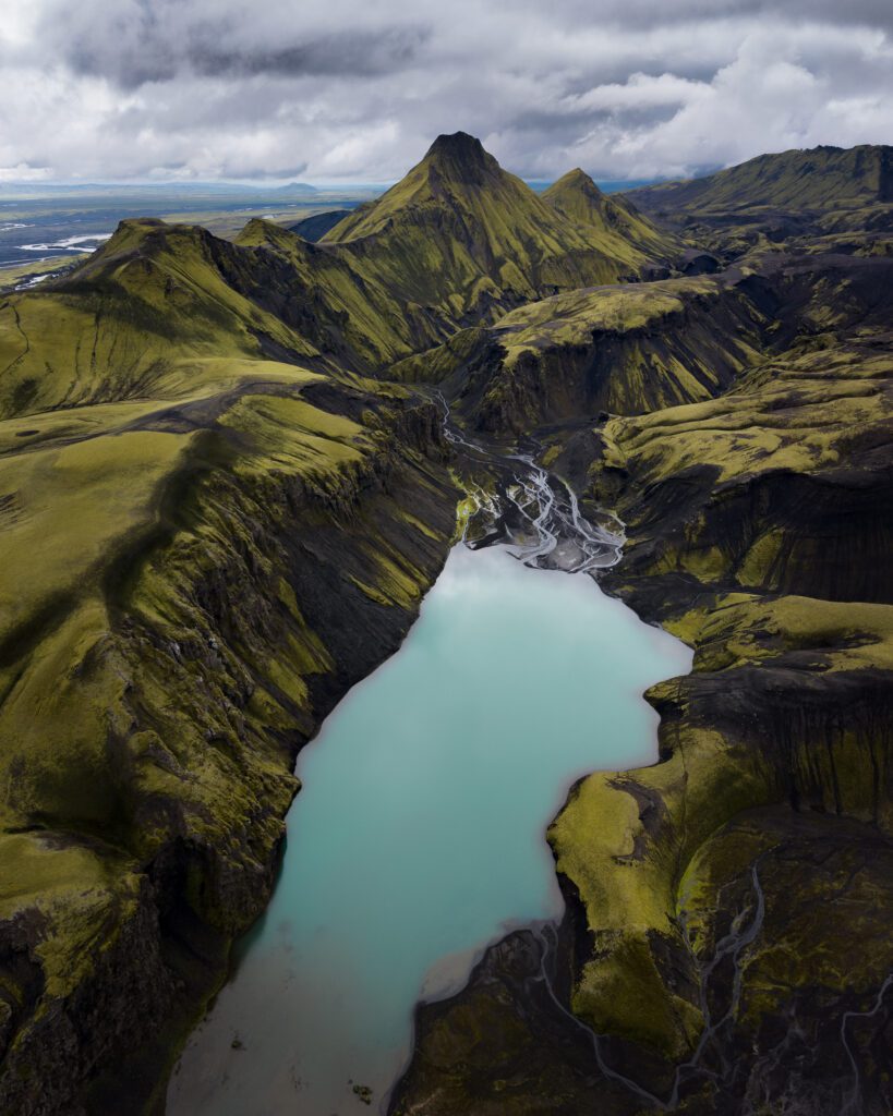 Turquoise lake nestled in steep green slopes with a sharp peak rising behind.