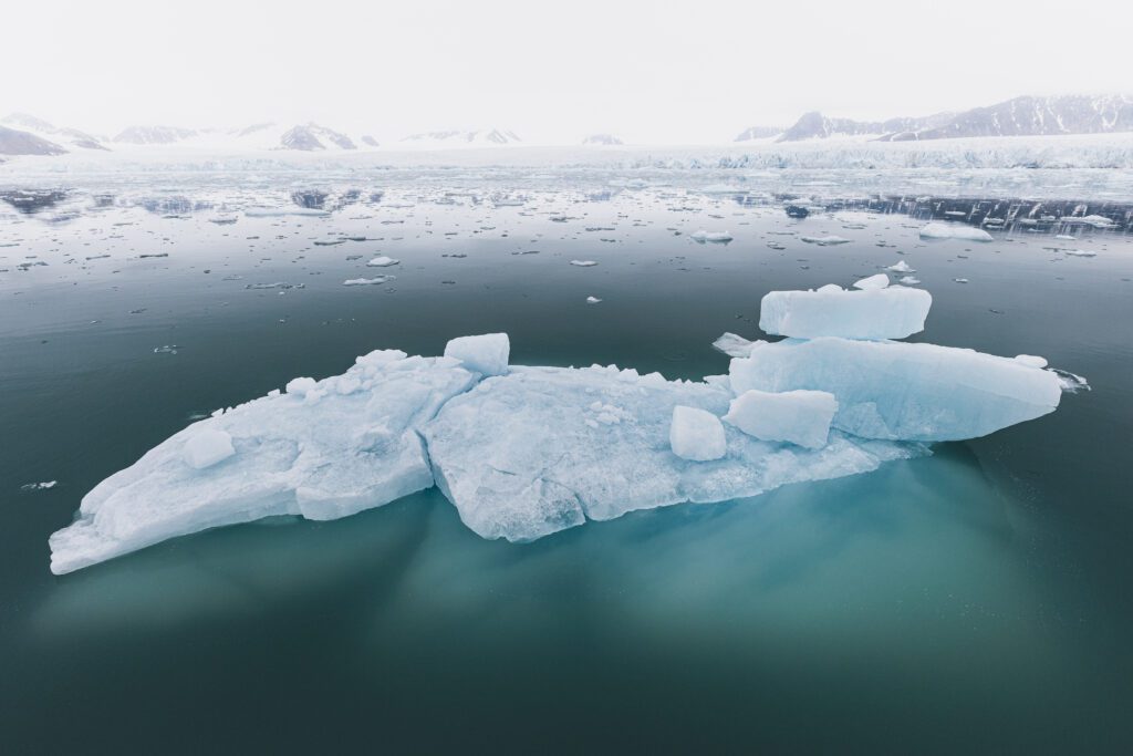 Floating iceberg fragment in calm water before a Svalbard glacier front.