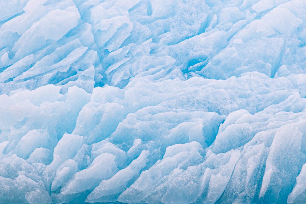 Abstract close-up of blue glacier ice with deep textured striations, Svalbard.