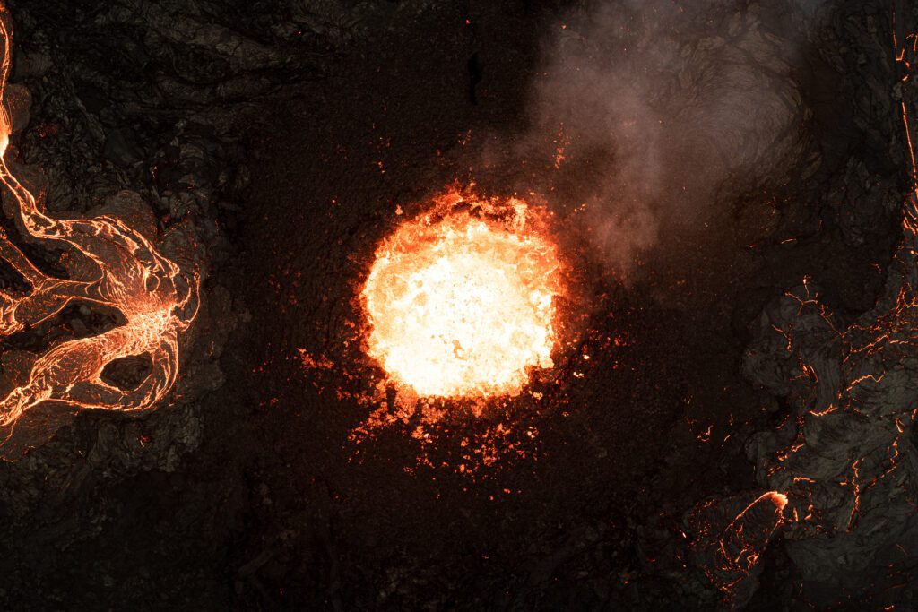 Top-down drone view of a fountaining crater vent with radiating lava channels.