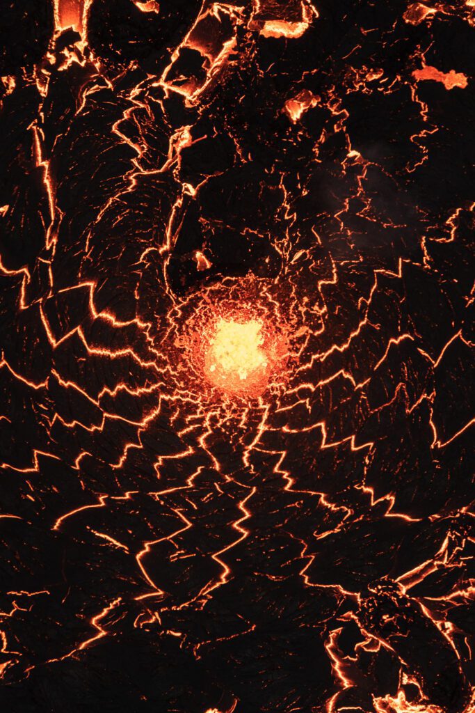 Top-down aerial of a glowing crater with starburst-cracked cooling crust.