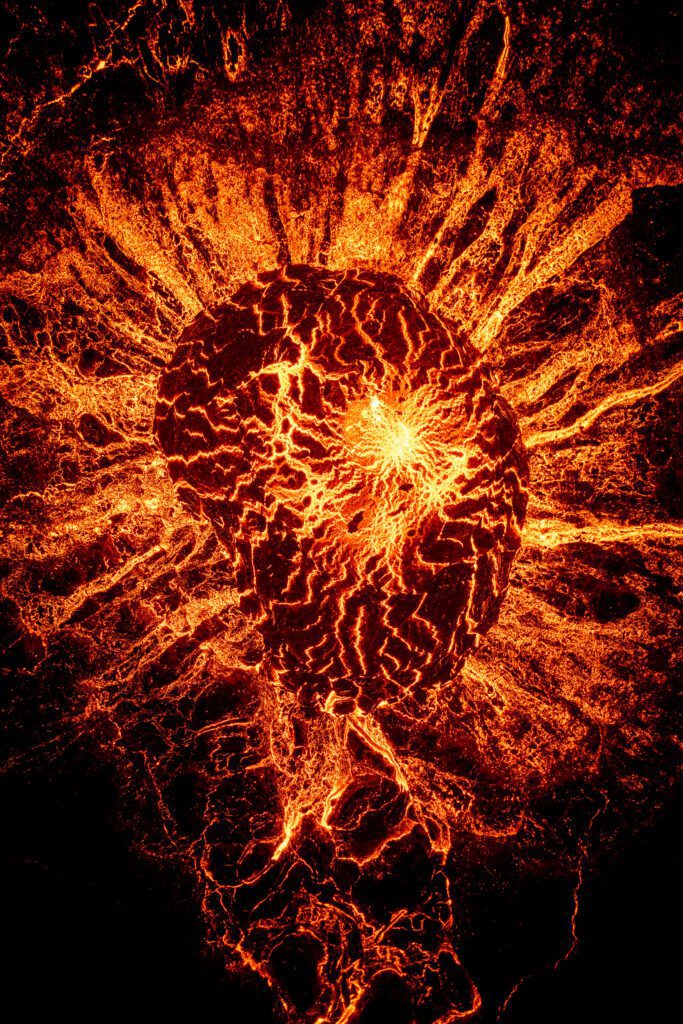 Top-down aerial of a heart-shaped erupting crater with radiating lava channels.