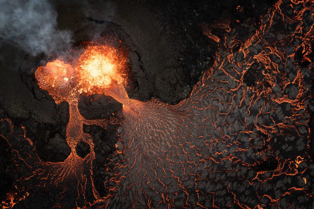 Aerial drone shot of a lava vent erupting with smoke at the Fagradalsfjall eruption in Iceland.