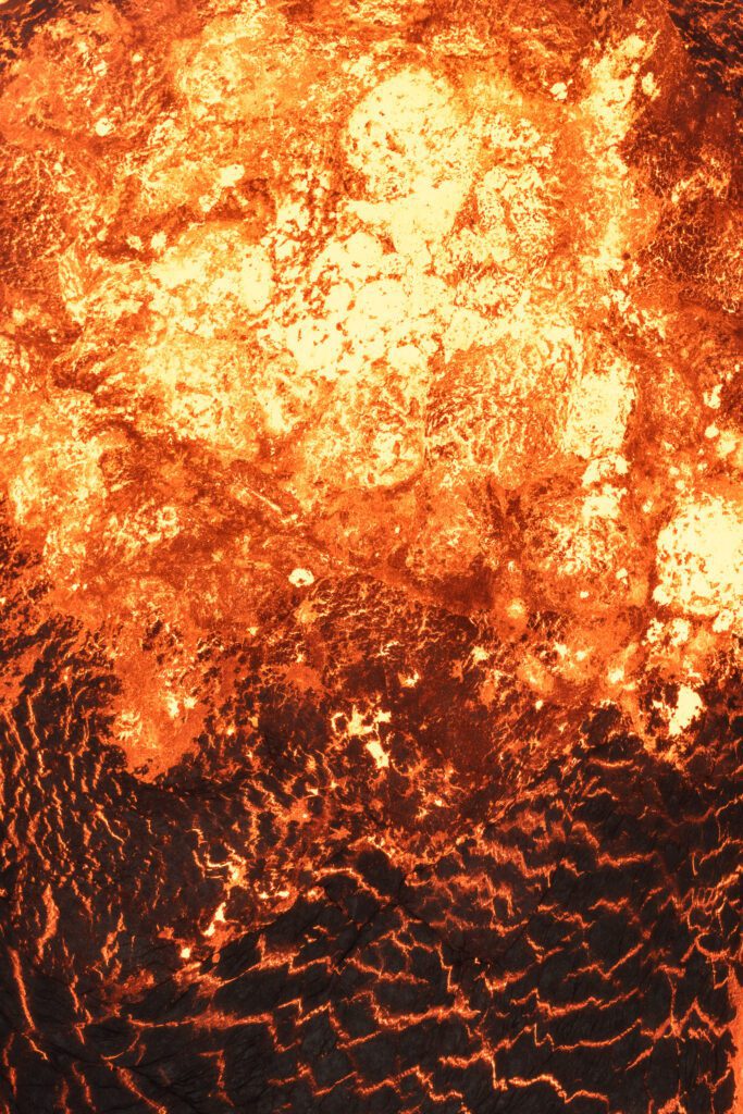 Top-down close-up of a churning bright lava lake surface with heat distortion.