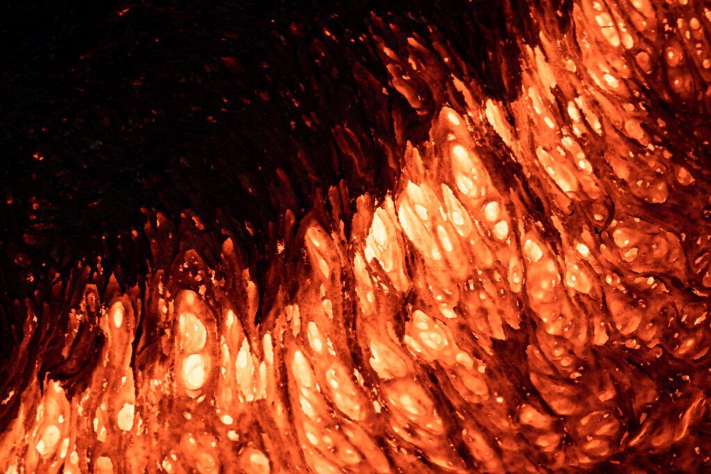 Abstract close-up of glowing pahoehoe lava with cracking crust.