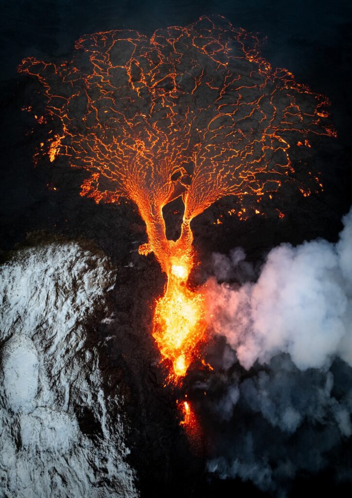 Aerial drone view of a tree-shaped lava breakout flowing across snow-covered ground.