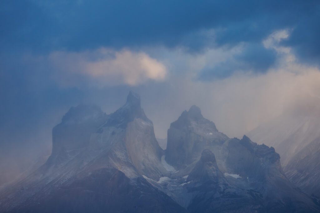 Los Cuernos del Paine veiled in mist and passing rain at dusk.