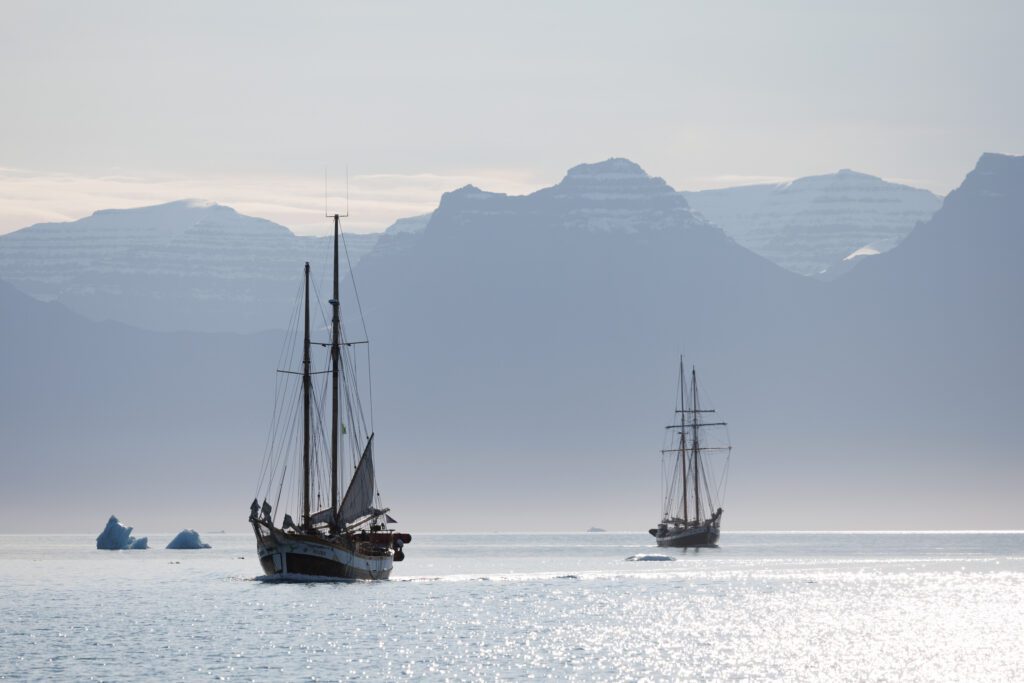 Eastern Greenland: Exploring The Solitude of Scoresbysund Two sailboats sailing through East Greenland in Scoresbysund