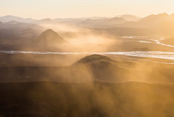 Golden hour light streaming across the volcanic hills of the Icelandic Highlands from above.